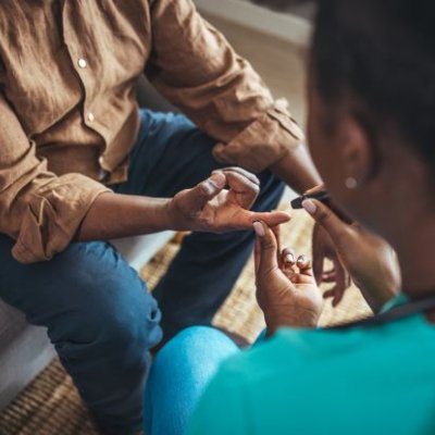 Woman taking blood sugar level of patient